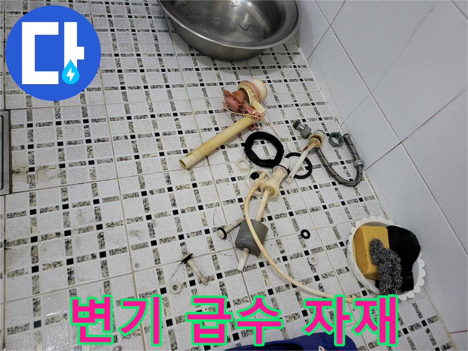 바닥 타일 위에 놓인 변기용 급수 밸브와 고무 패킹 및 호스