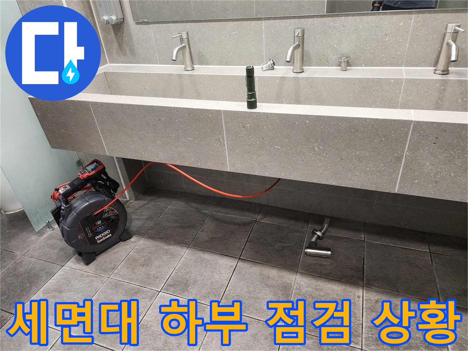 화장실 세면대 아래 배수 배관과 검사용 장비의 모습