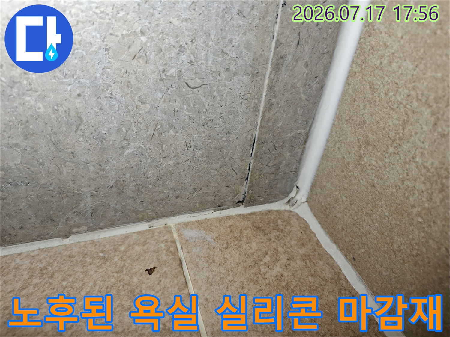 타일과 타일이 만나는 수직 모서리의 백색 실리콘이 갈라지고 오염된 상태의 근접 사진