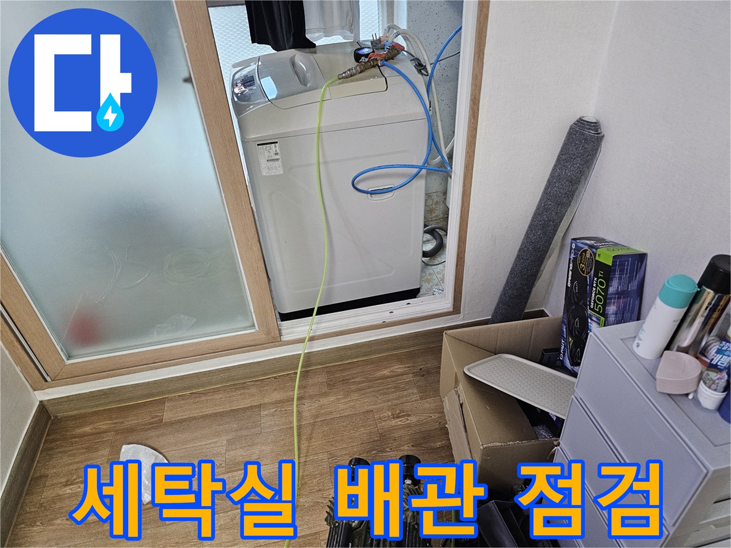 세탁기 주변의 파란색 호스와 노란색 측정 장비가 놓여 있는 모습