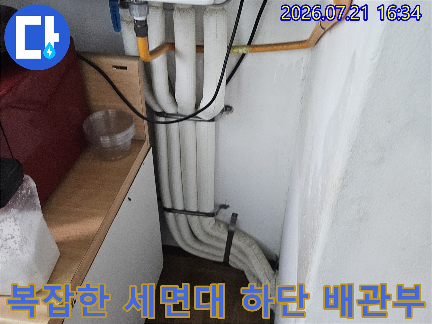 세면대 아래에 위치한 여러 가닥의 수도 및 급수 배관 시스템 점검 사진