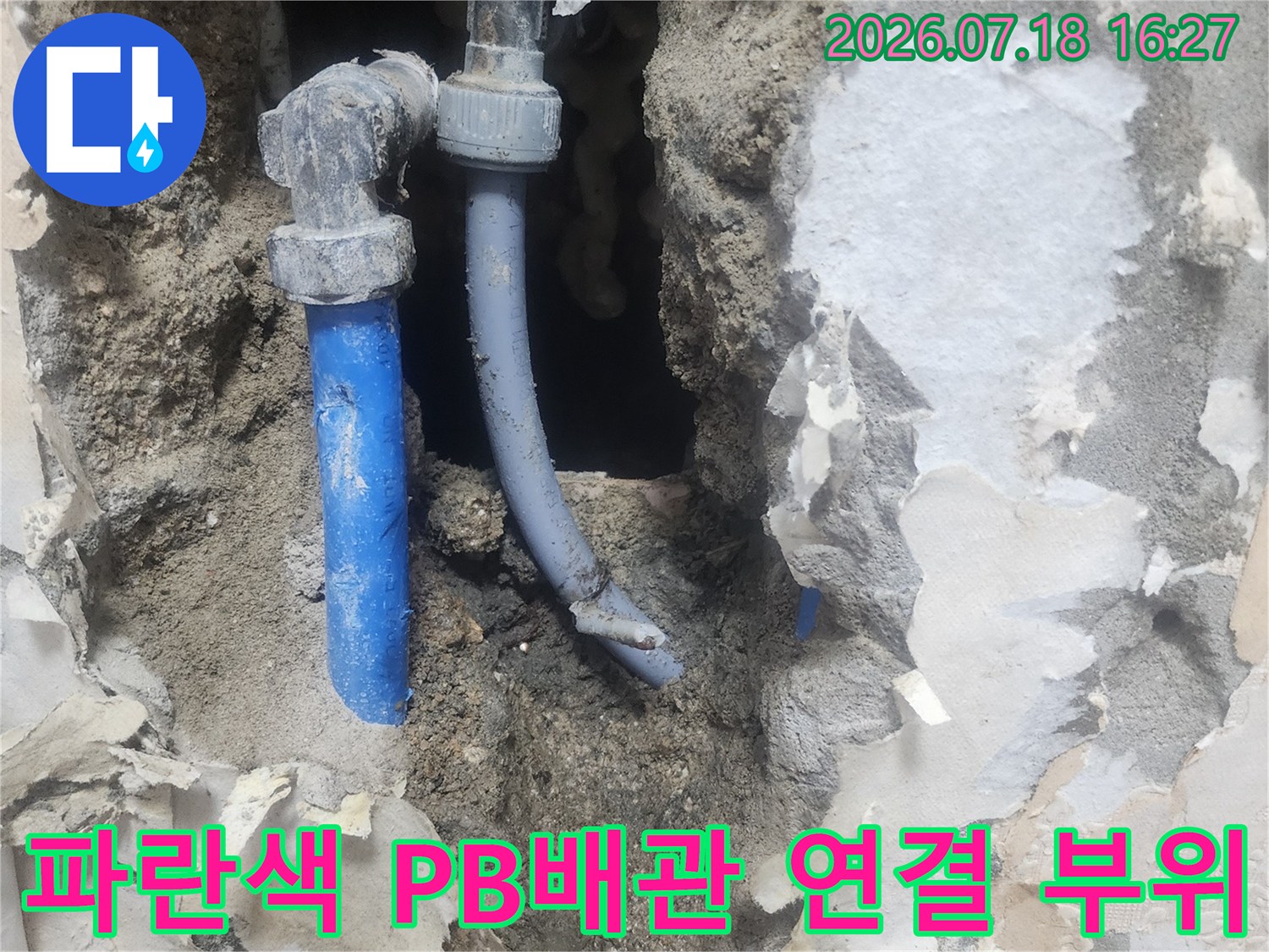 벽면을 파내어 노출시킨 파란색 수도 배관의 엘보우 연결 지점 사진