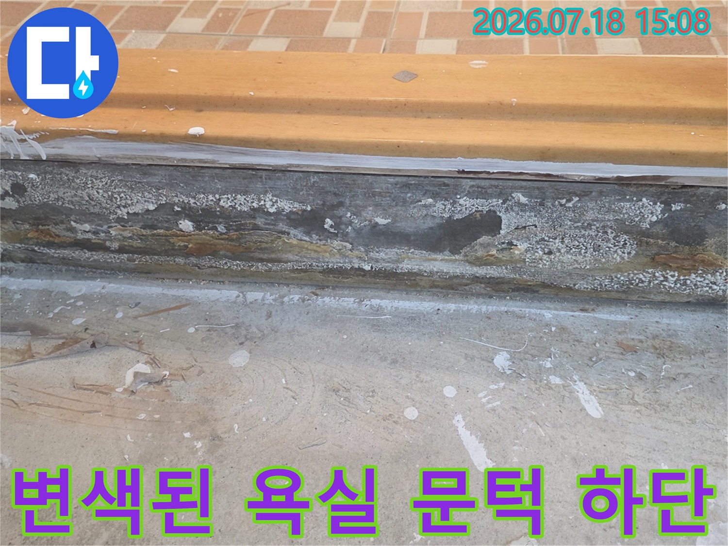화장실 입구의 목재 문턱 아랫부분이 습기를 먹어 검게 변하고 부식된 사진