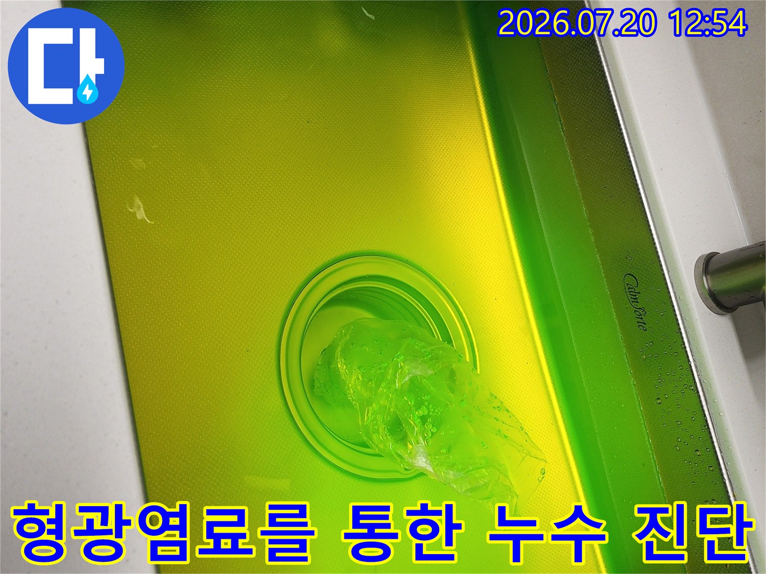 스테인리스 싱크대에 노란색 형광 염료가 채워져 하수관으로 흐르는 모습-사진