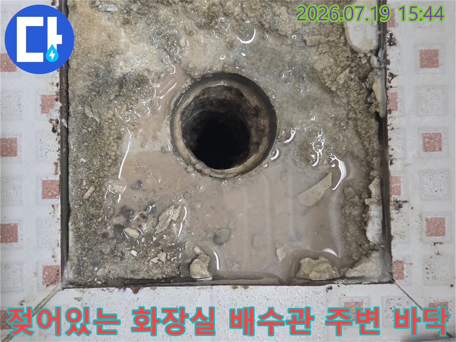 타일이 제거된 구역의-배수구 주변 시멘트가-축축하게 젖어 있고 얼룩진 모습