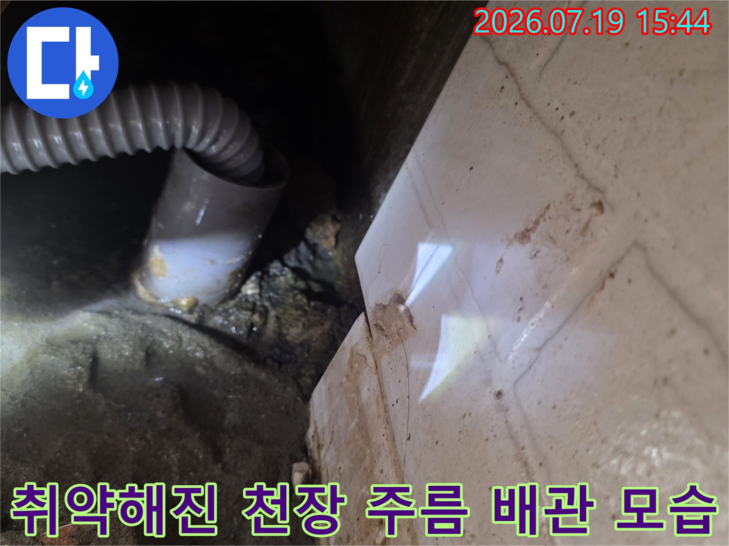 흰색-타일-마감재와-인접한-천장-내부의-회색-주름-배수관