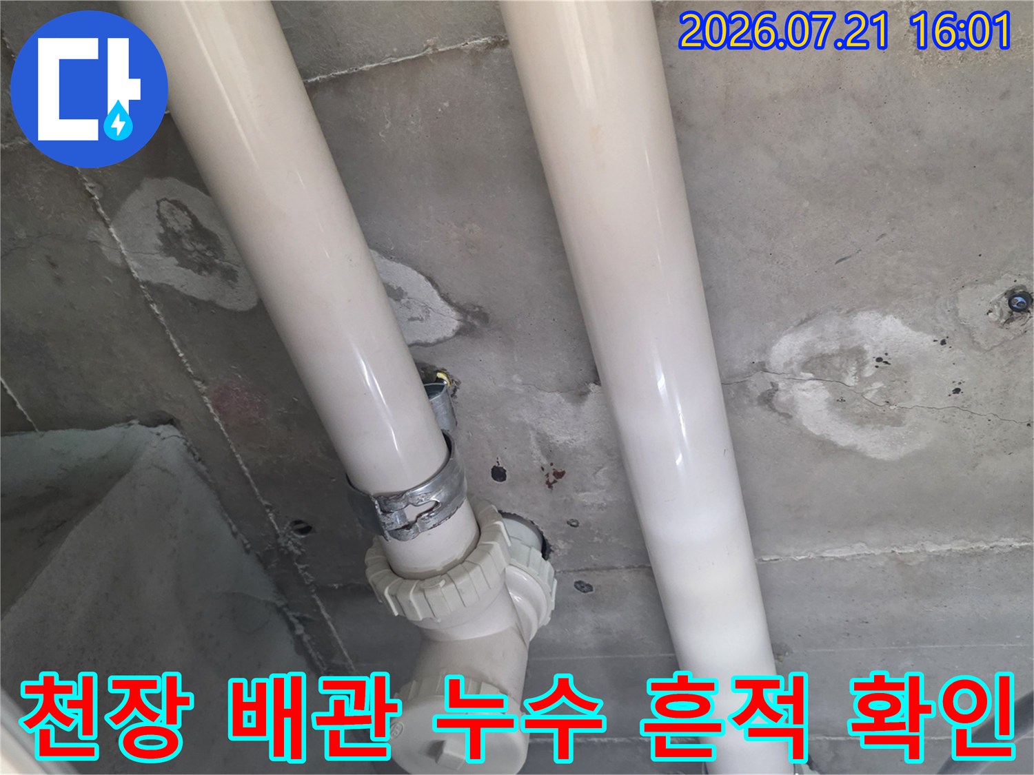 상부층에서 떨어진 물로 인해 변색된 천장 콘크리트와 흰색 배관