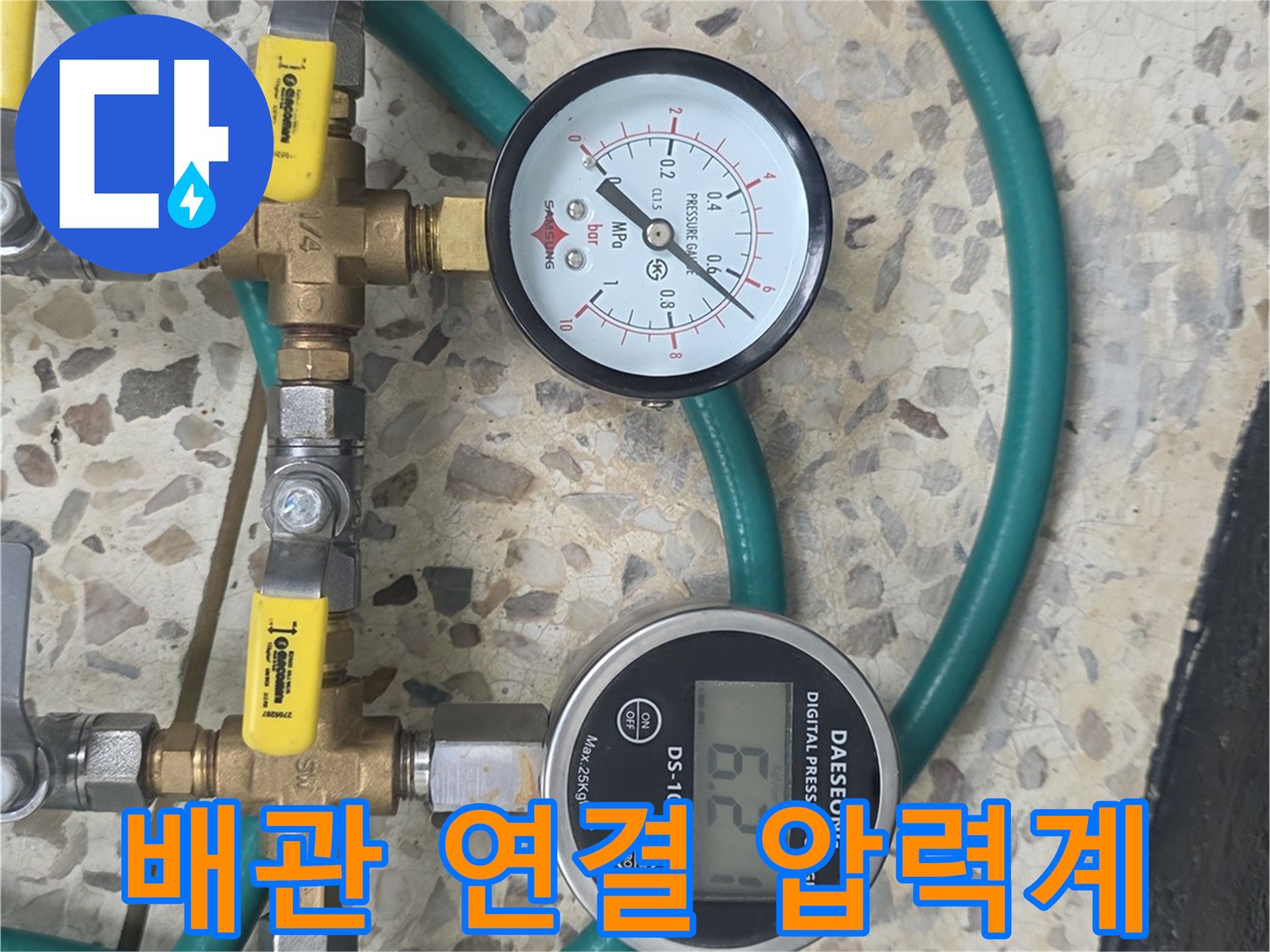 금색 황동 부속과 초록색 호스가 연결된 압력 측정 장치