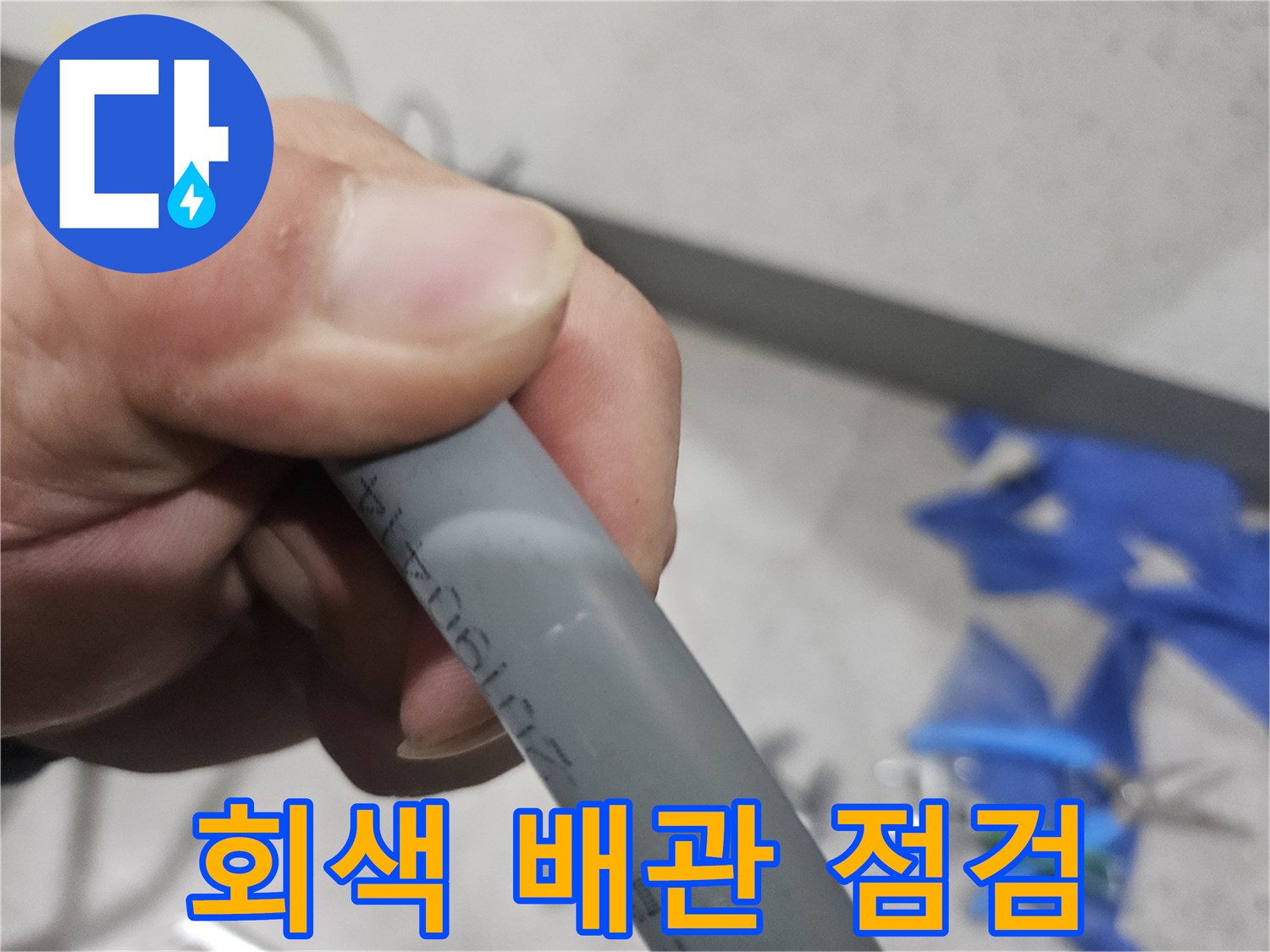 누수 확인을 위해 손으로 잡고 있는 회색 배관
