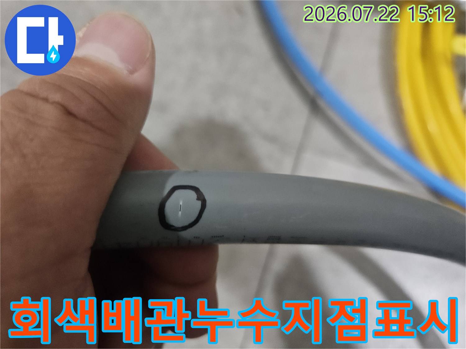 손으로 회색 수도 배관의 특정 부분을 잡고 누수 지점을 동그라미로 표시한 모습