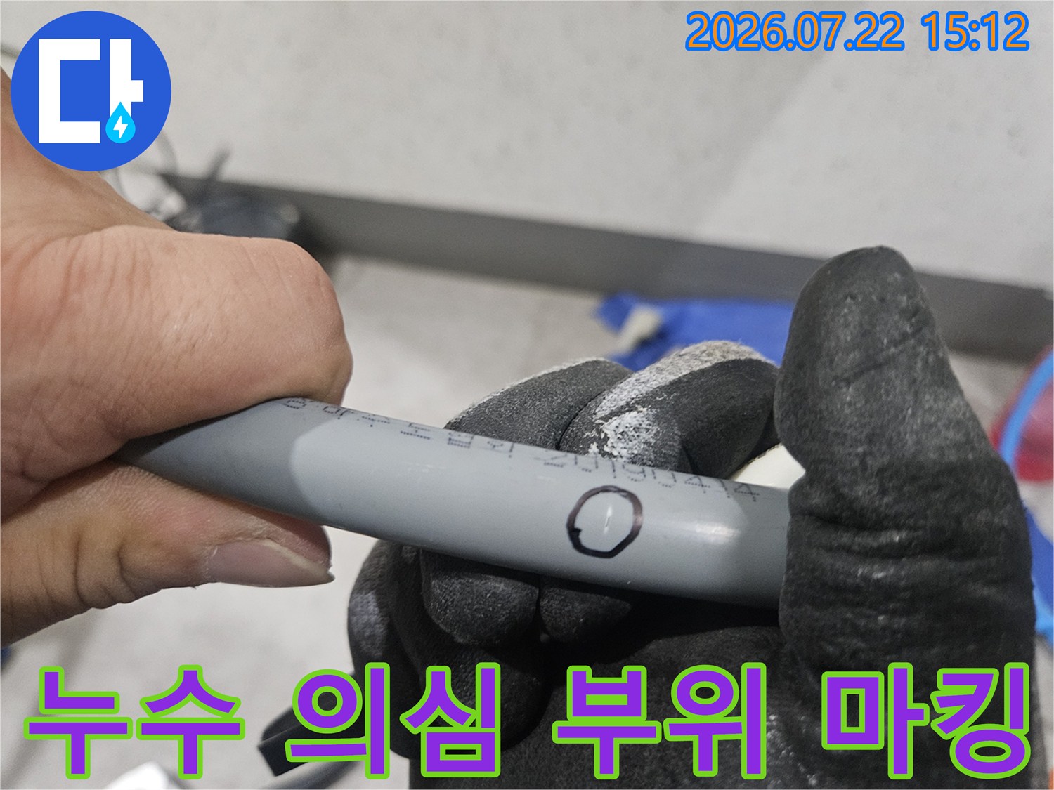 작업자가 장갑을 낀 손으로 회색 플라스틱 배관의 결함 위치를 동그라미로 표시한 사진