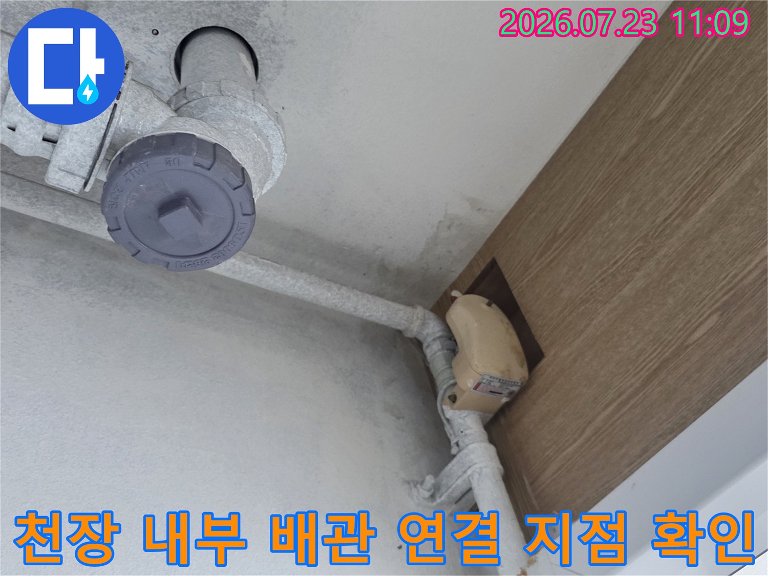 회색의 굵은 배관과 천장 마감재가 만나는 지점에 발생한 누수 흔적-사진