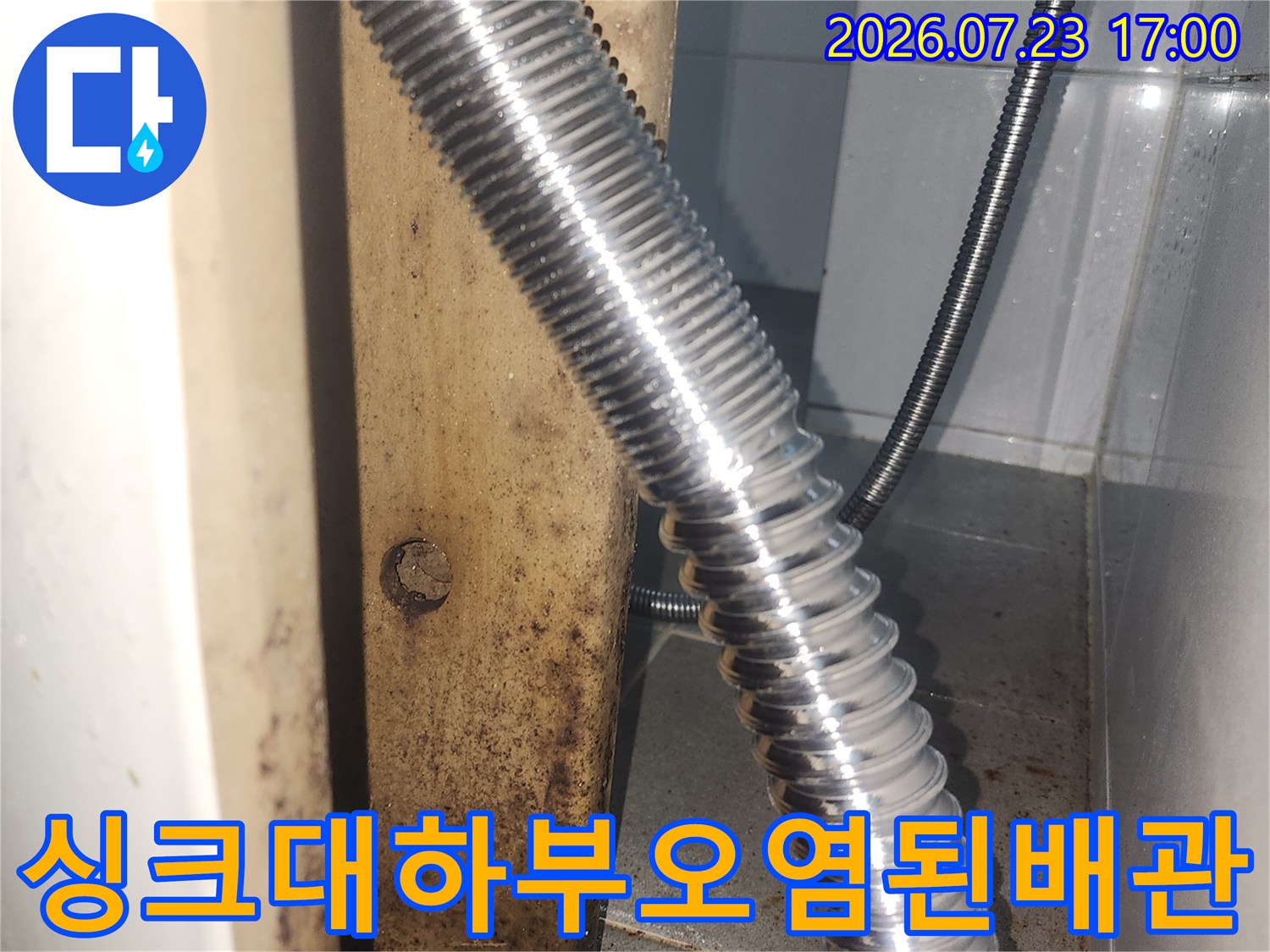 벽체 배수구와 연결된 금속 주름관 주변의 갈색 오염 흔적-누수 징후 사진