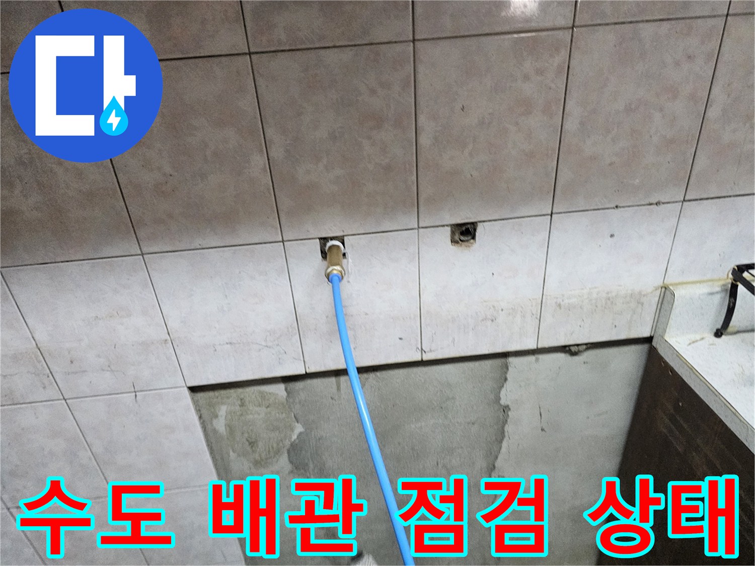 벽면 타일 사이로 연결된 파란색 점검용 호스 모습