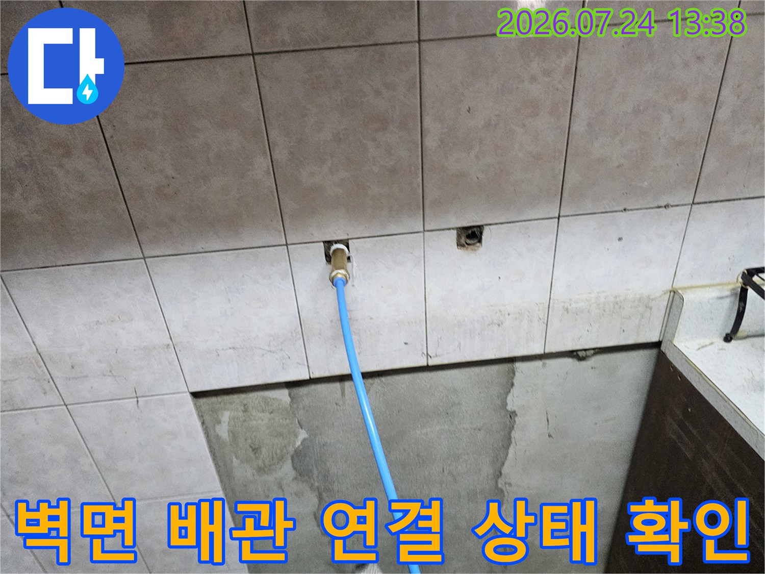 타일 벽면에 파란색 호스가 연결되어 있는 누수 점검 현장 사진