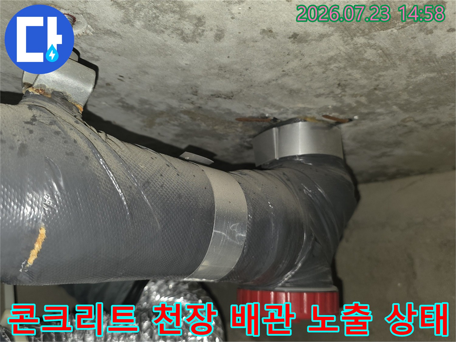 거친 콘크리트 표면의 천장에 설치된 회색 배관-전경