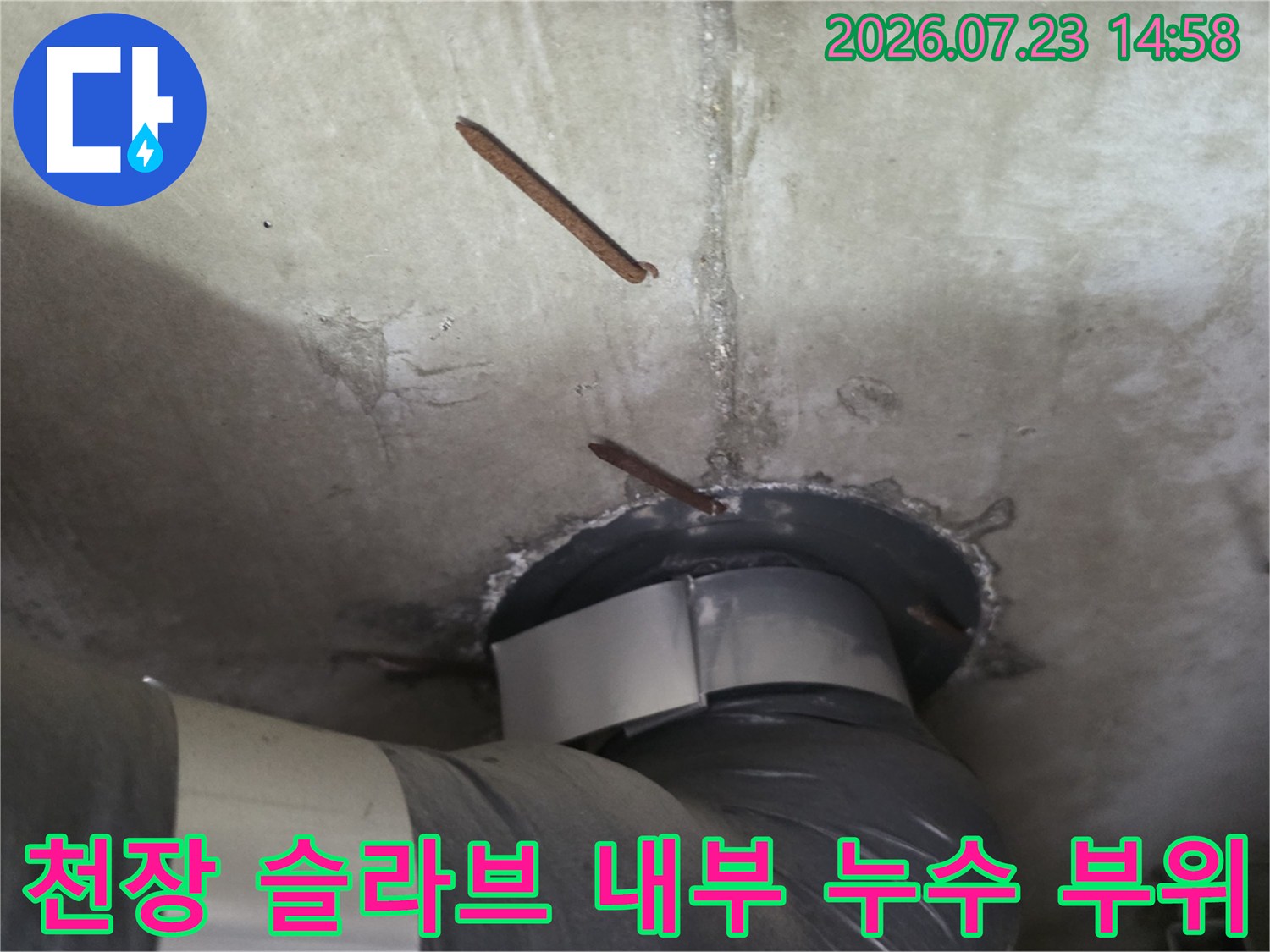 부식된 철근이 노출되고 배관이 연결된 천장 콘크리트 단면