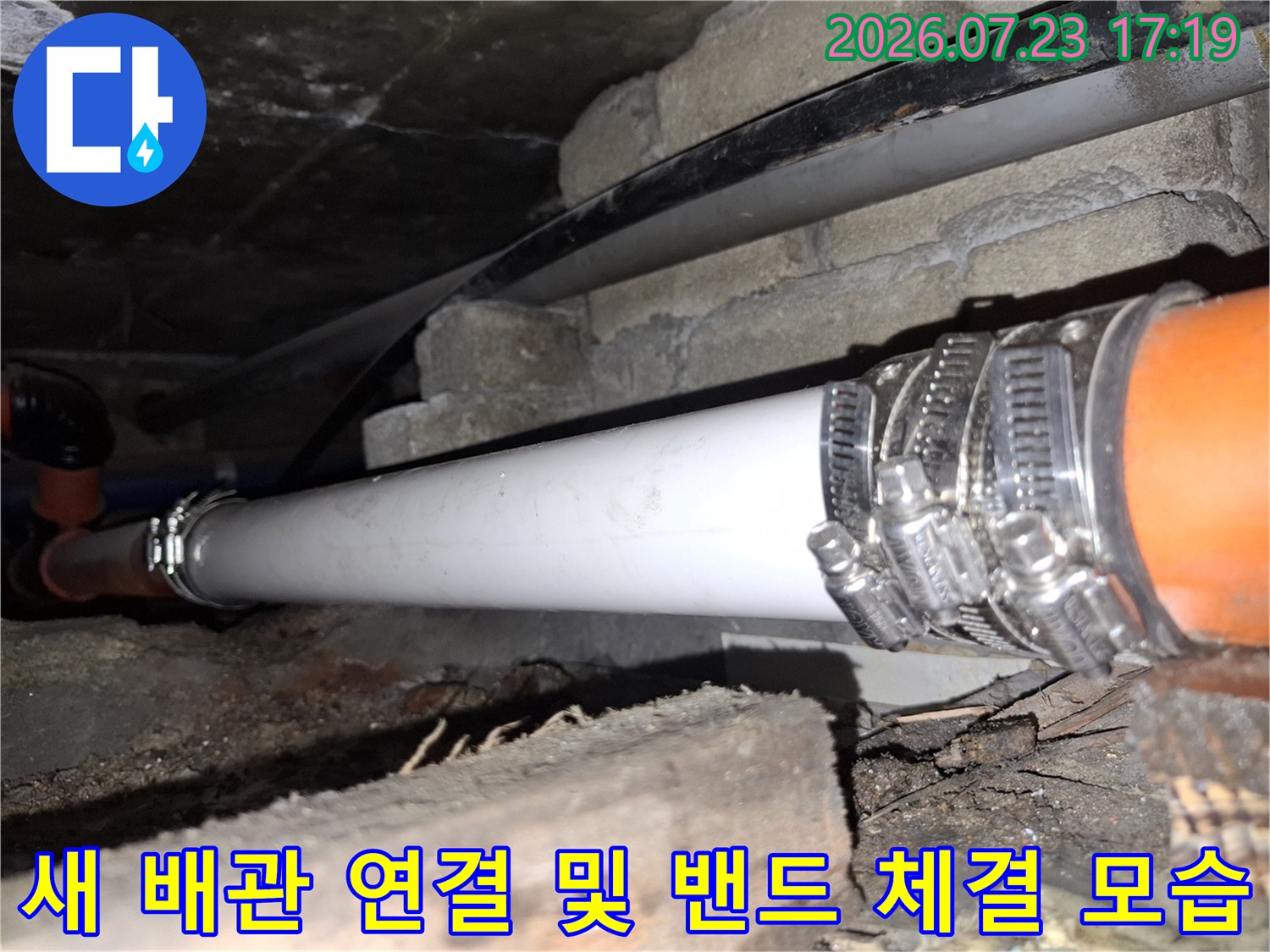 부식된 배관을 잘라내고 흰색 PVC 관을 연결한 뒤 금속 호스 밴드로 마감한 사진