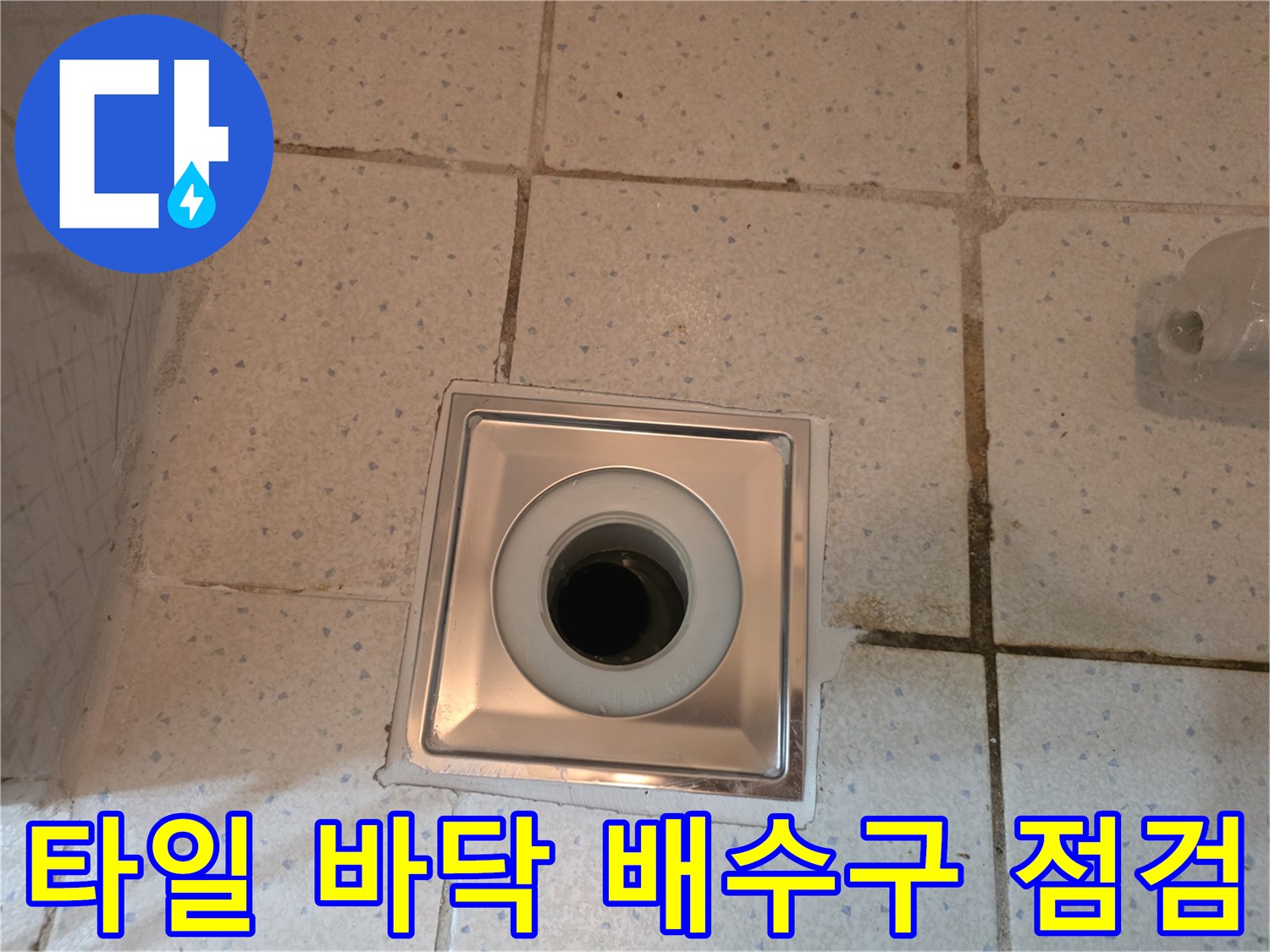 하얀색 타일로 마감된 바닥의 금속 재질 배수구 유가