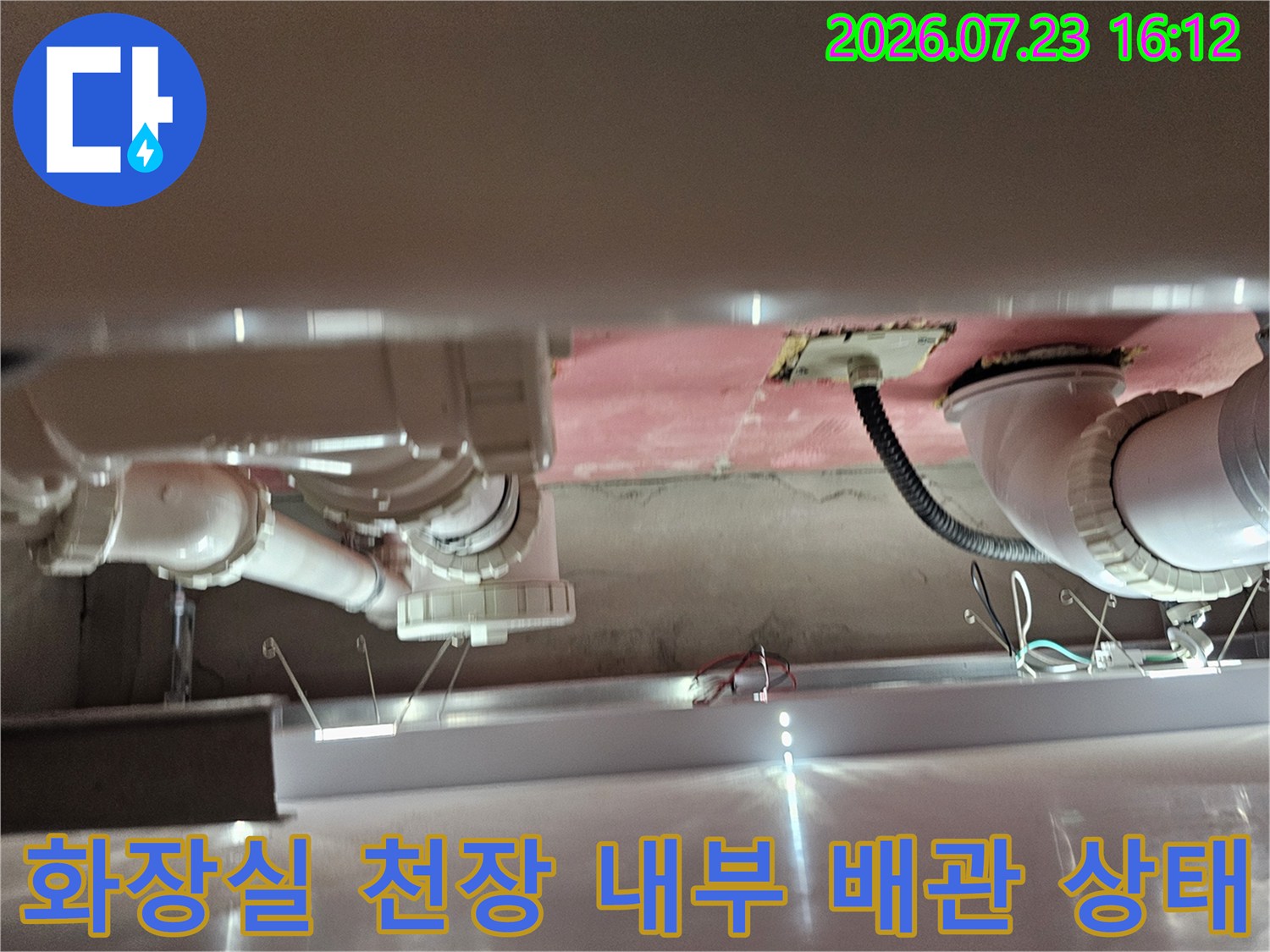 분홍색 단열재가 부착된 천장 속에 설치된 하얀색 플라스틱 배관-연결부 모습