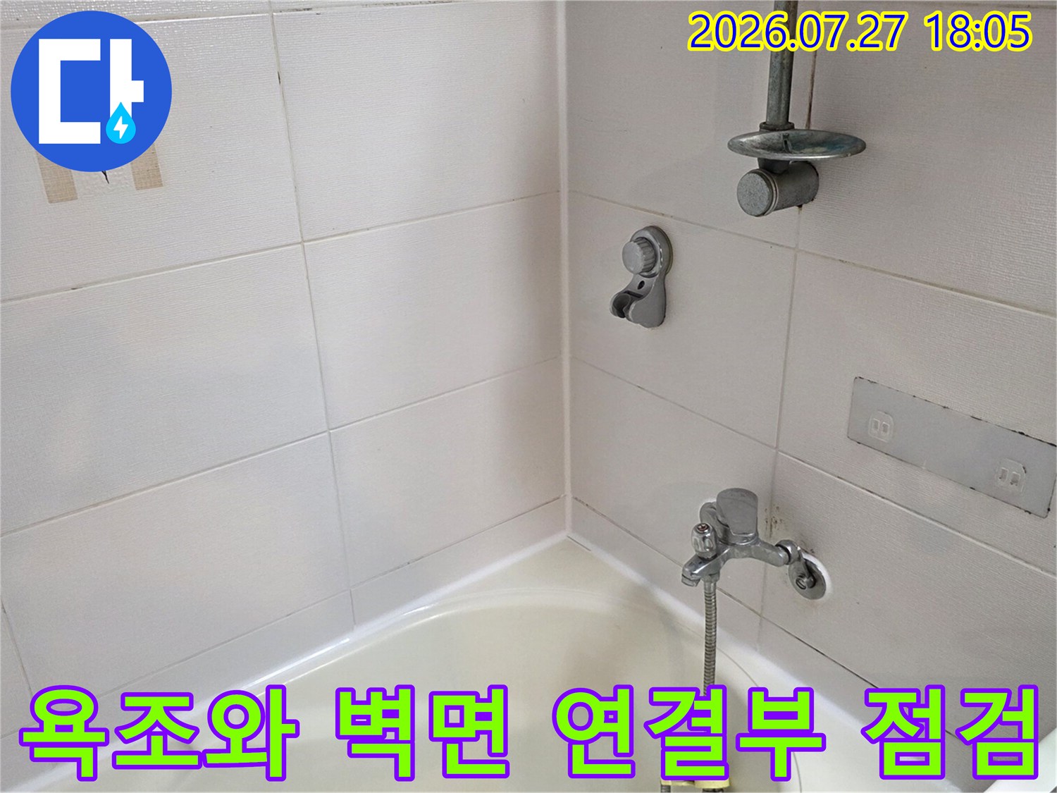 흰색 타일로 마감된 욕실 내부에 설치된 수전과 욕조-벽면 접합 부위 모습