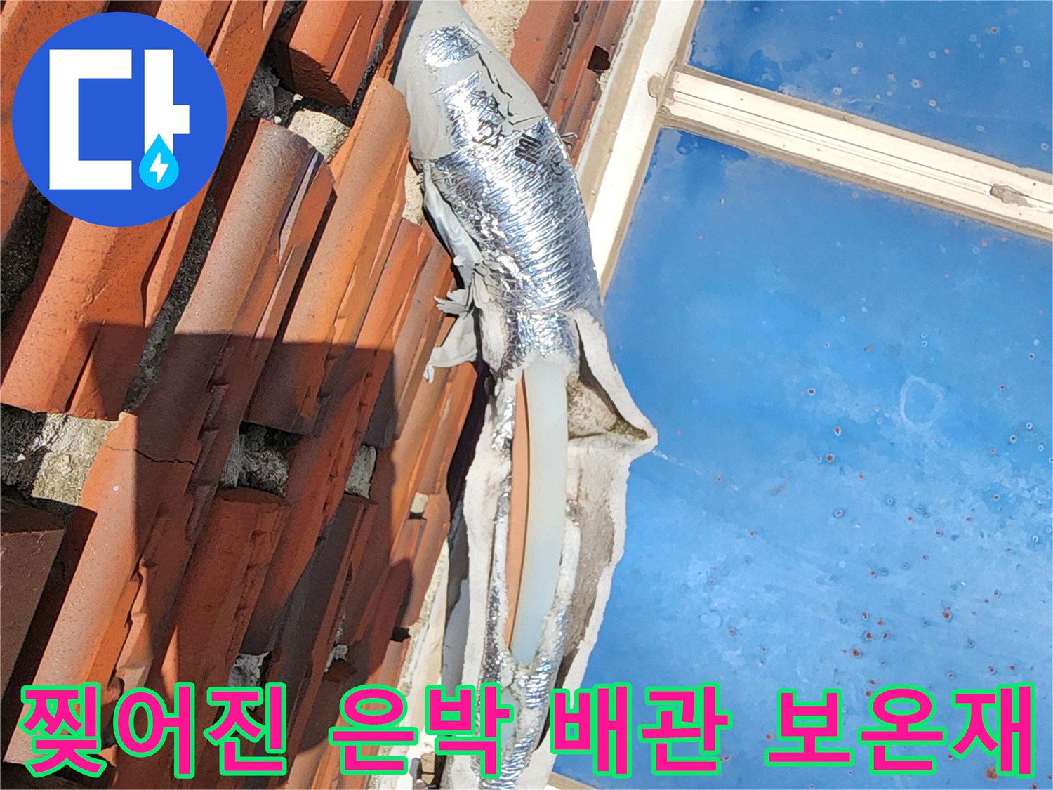 기왓장 아래 훼손된 은박 보온재로 감싸진 수도 배관