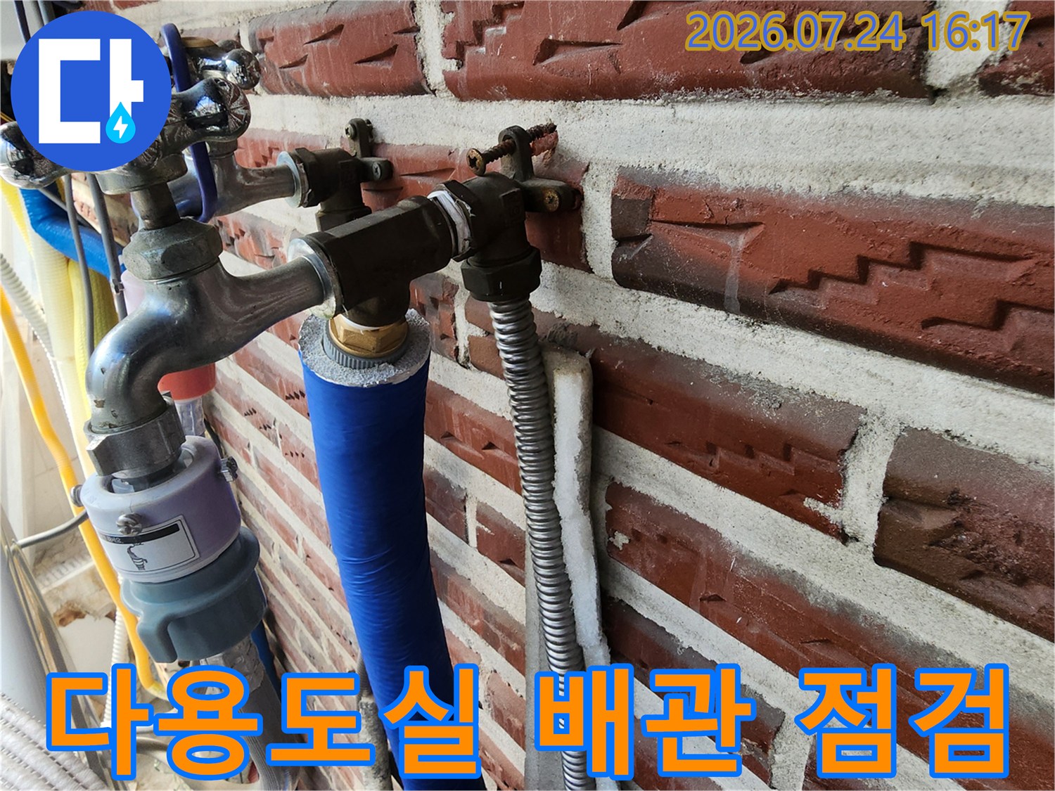 벽돌 벽면에 고정된 파란색 보온재 및 은색 단열재 배관 구조물