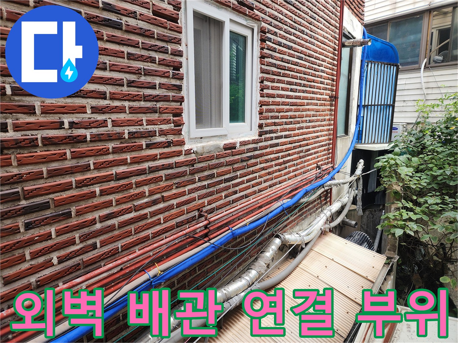 벽돌 외벽과 연결된 다수의 외부 노출 배관들