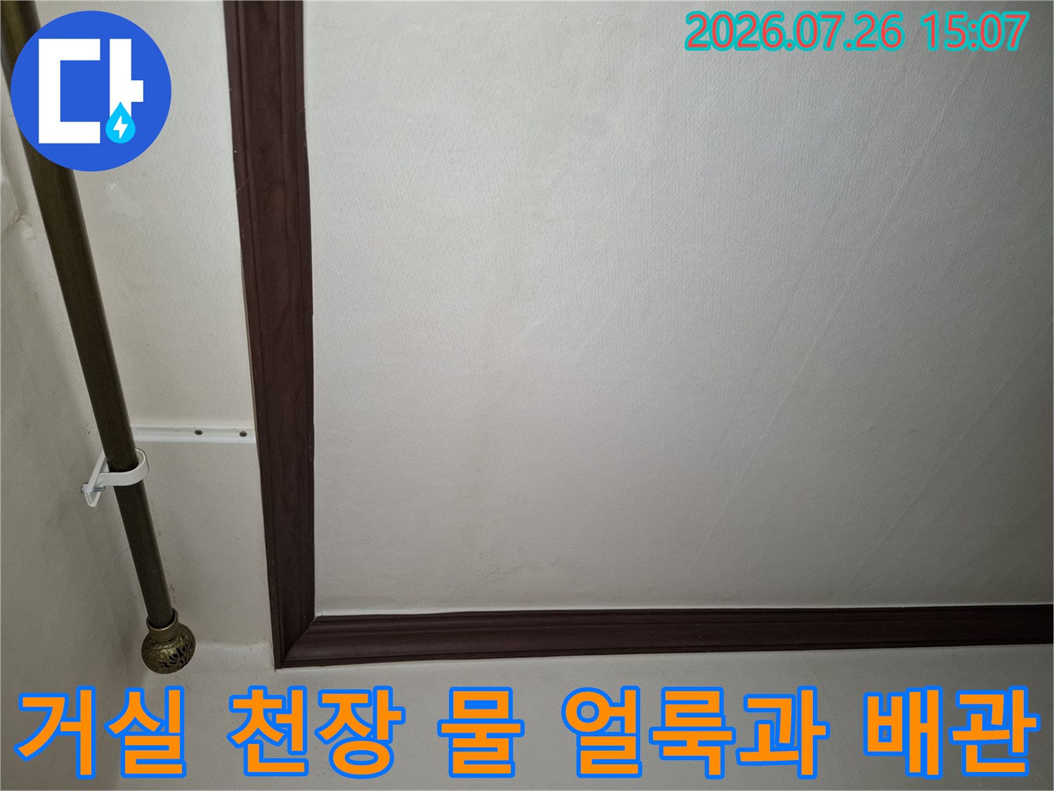 거실 천장에 발생한 누수 흔적과 옆으로 지나가는 금속 배관의 모습