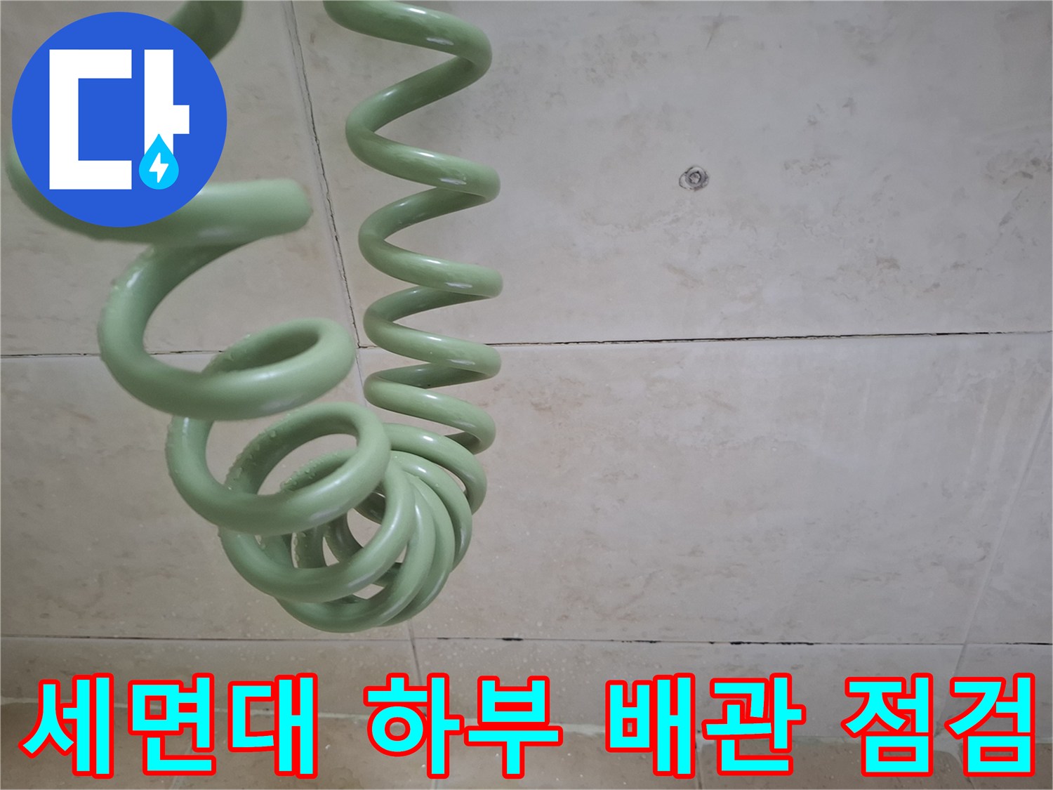 초록색 뱀 모양 배관과 타일 벽면의 접촉 부위