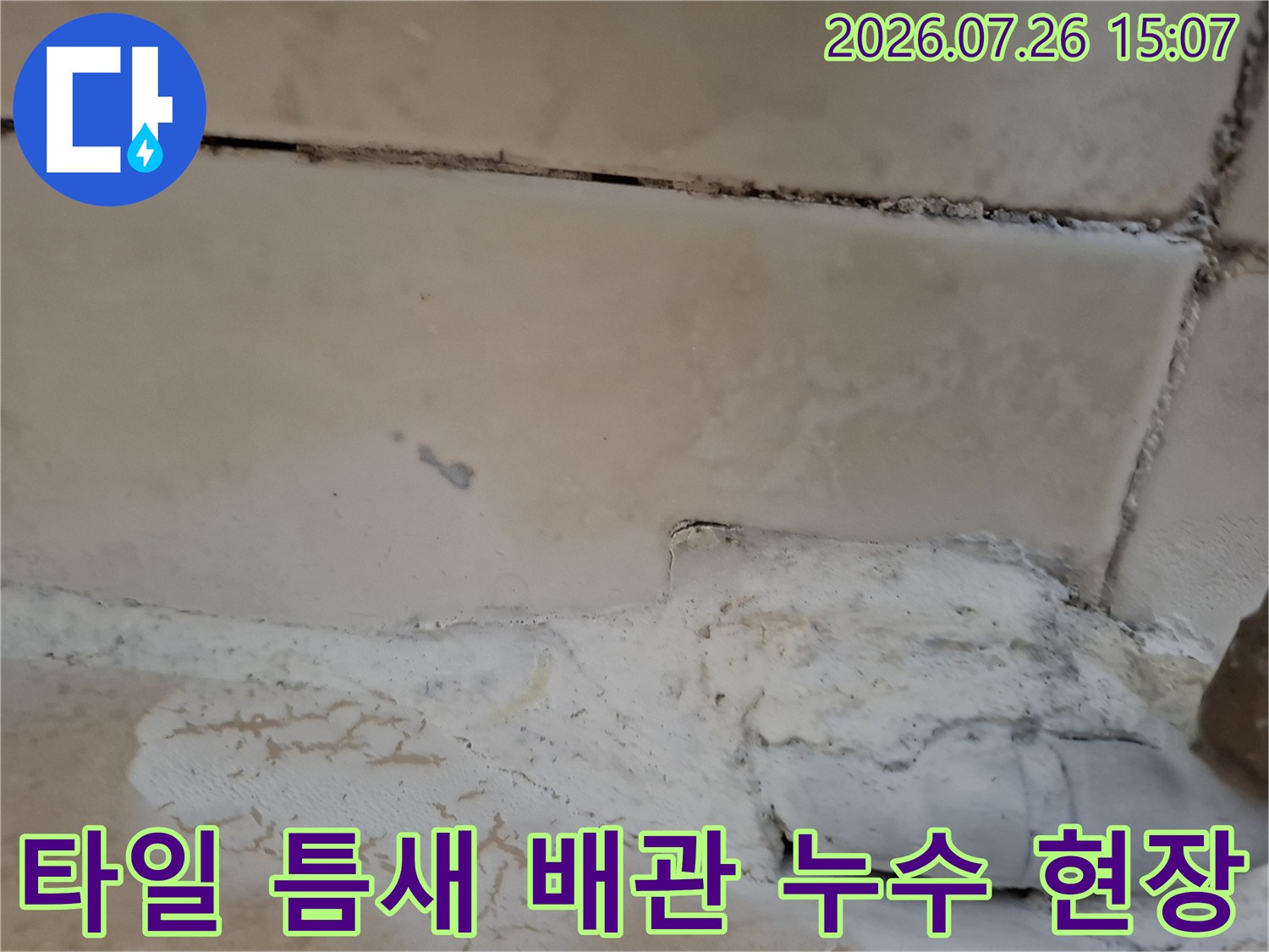 하얀색 플라스틱 배관과 타일 경계면의 마감재가 탈락하여 틈이 생긴 사진