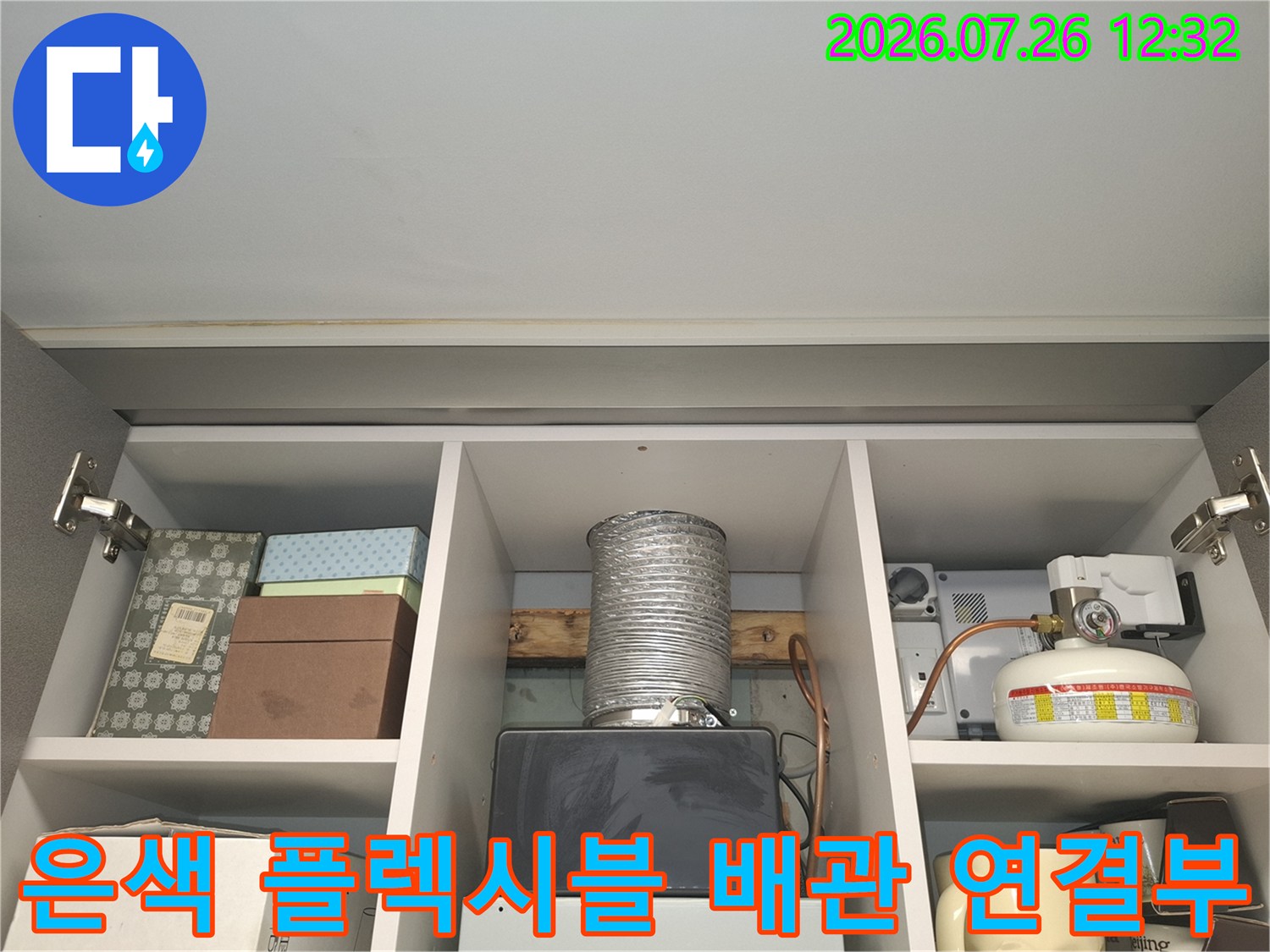 선반 칸에 배치된 은색 주름관 형태의 배관과 가스 관련 장치-사진