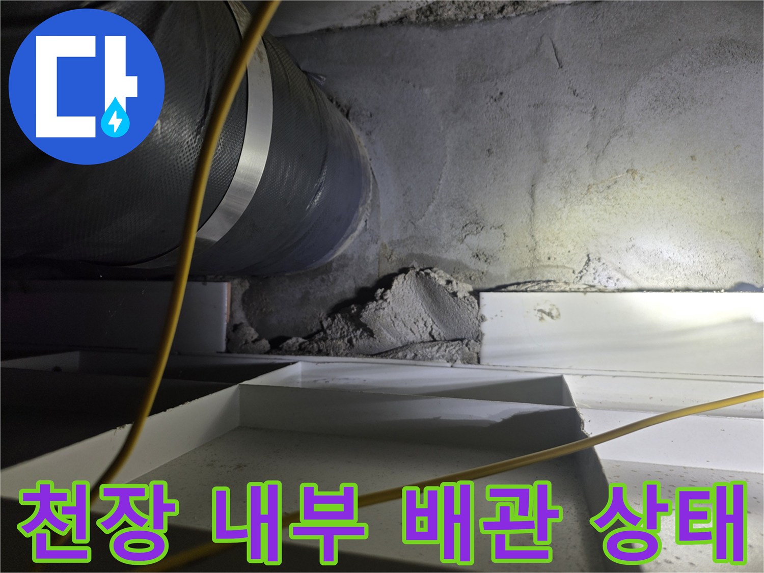 천장 구조물 사이의 굵은 배관과 콘크리트 벽면 모습