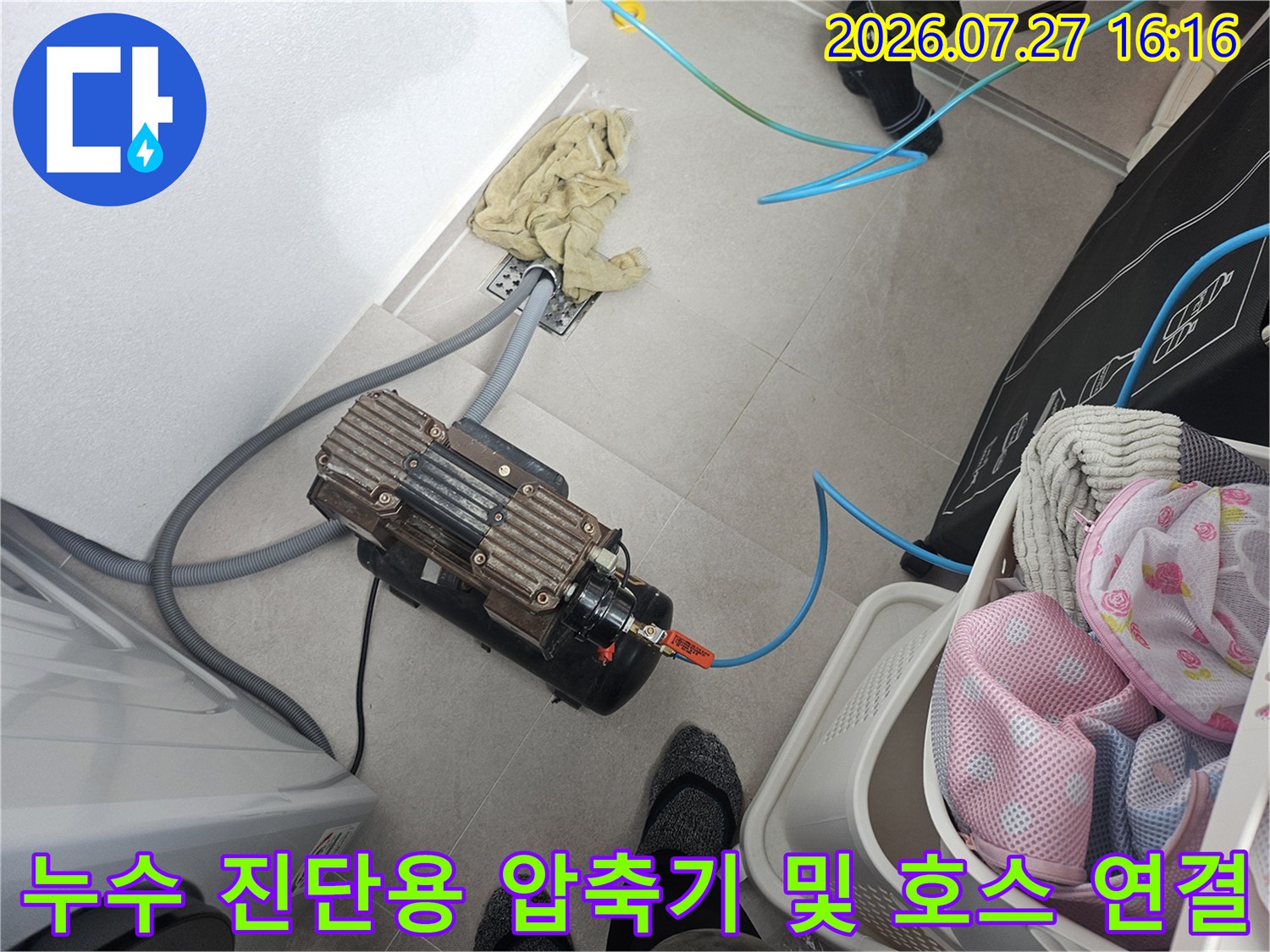 바닥에 놓인 공기압력 생성 장치-파란색 고무 호스와 배관 연결 모습