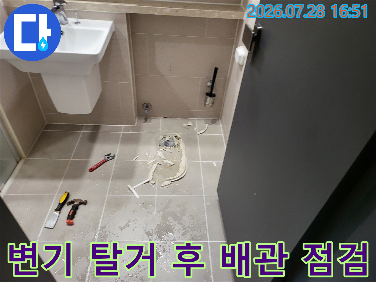 탈거된 변기 자리에 위치한 노출 배관과 작업용 공구들