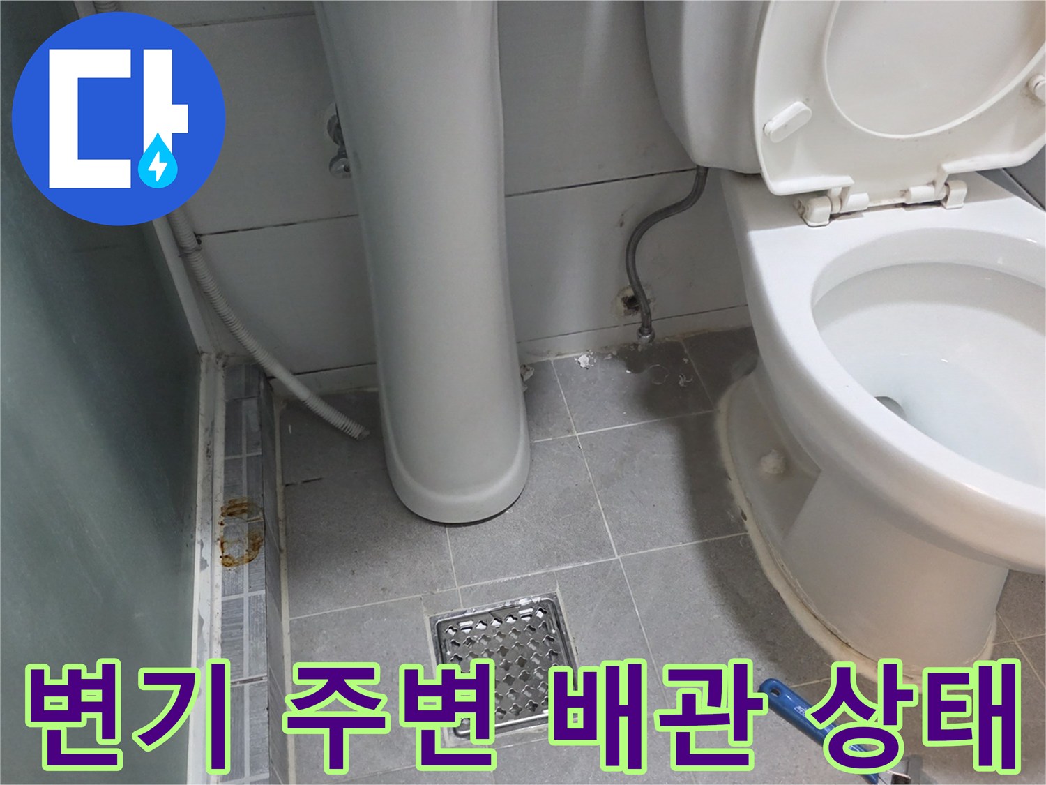 화장실 변기 옆 타일 바닥과 배수구 덮개 근접 사진