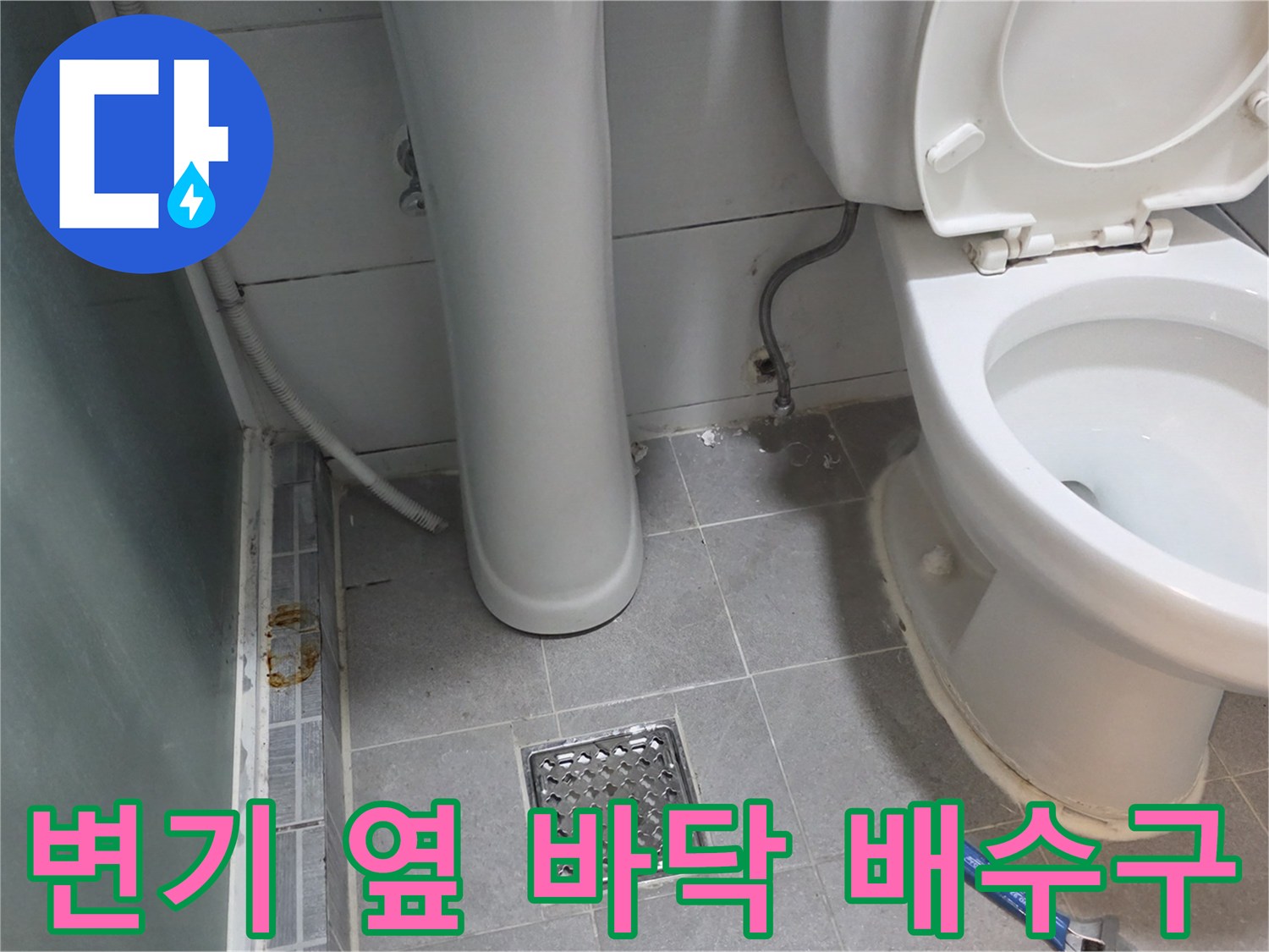 화장실 변기 옆쪽의 타일과 하수구 유가 모습입니다.
