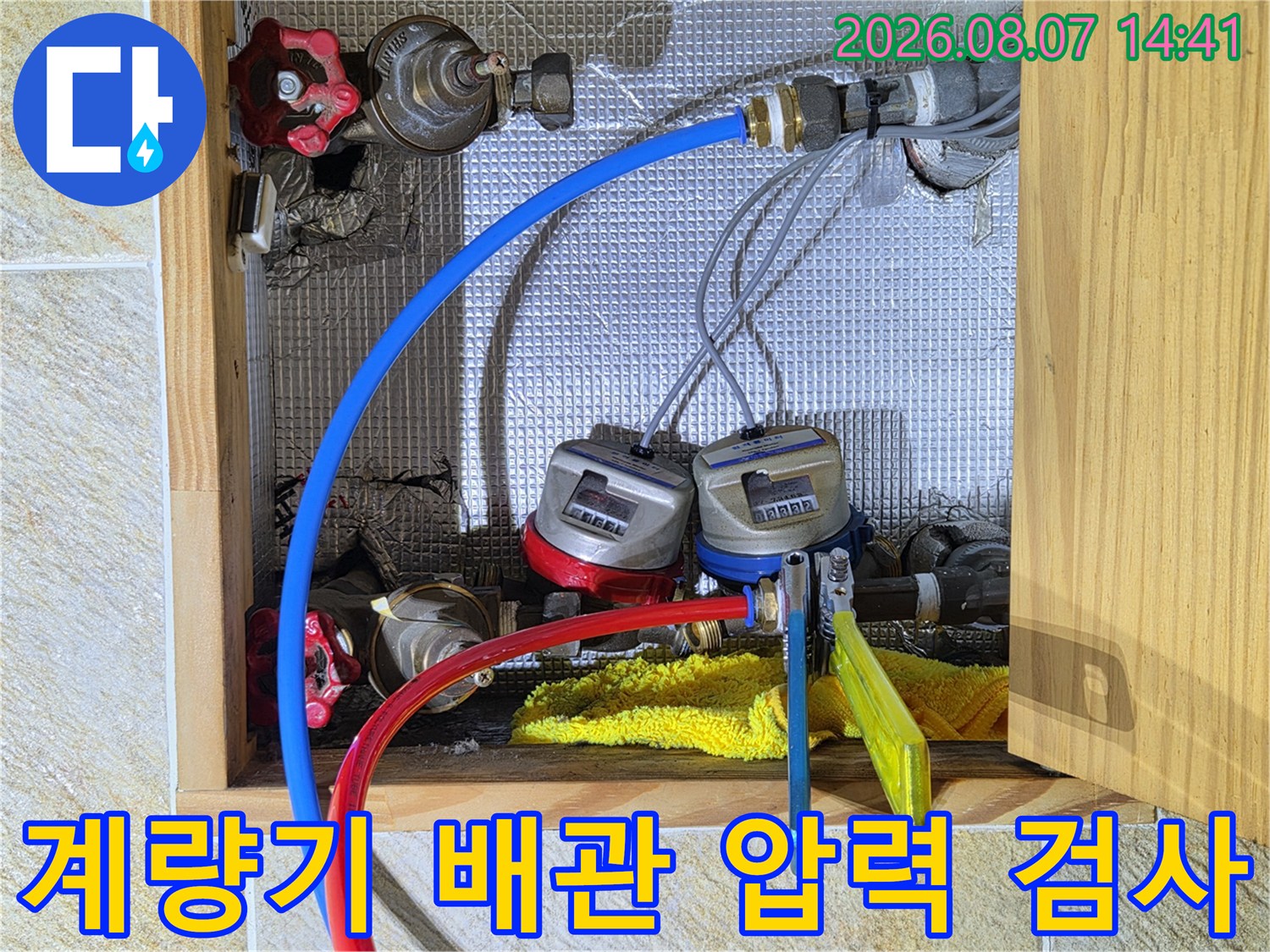 계량기에 연결된 파란색 빨간색 호스-수도 배관 누수 점검 장면