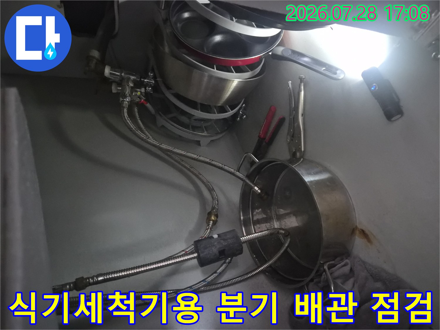 싱크대 하부에서 식기세척기 전용 분기 배관과 밸브를 확인하는 모습