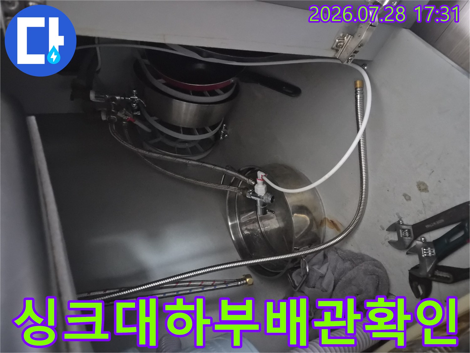 싱크대 하부장에서 식기세척기 연결 배관을 점검하는 모습
