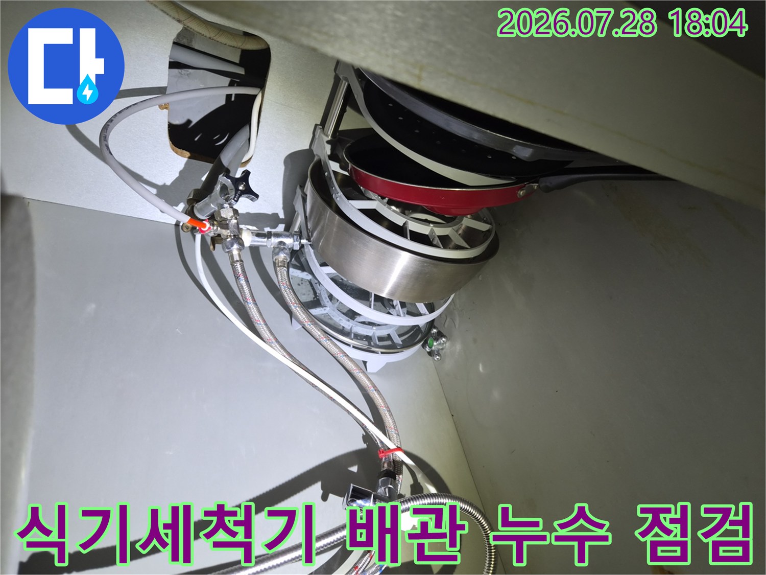싱크대 하부장의 식기세척기 연결 부위와 급수 배관을 정밀하게 확인하는 모습