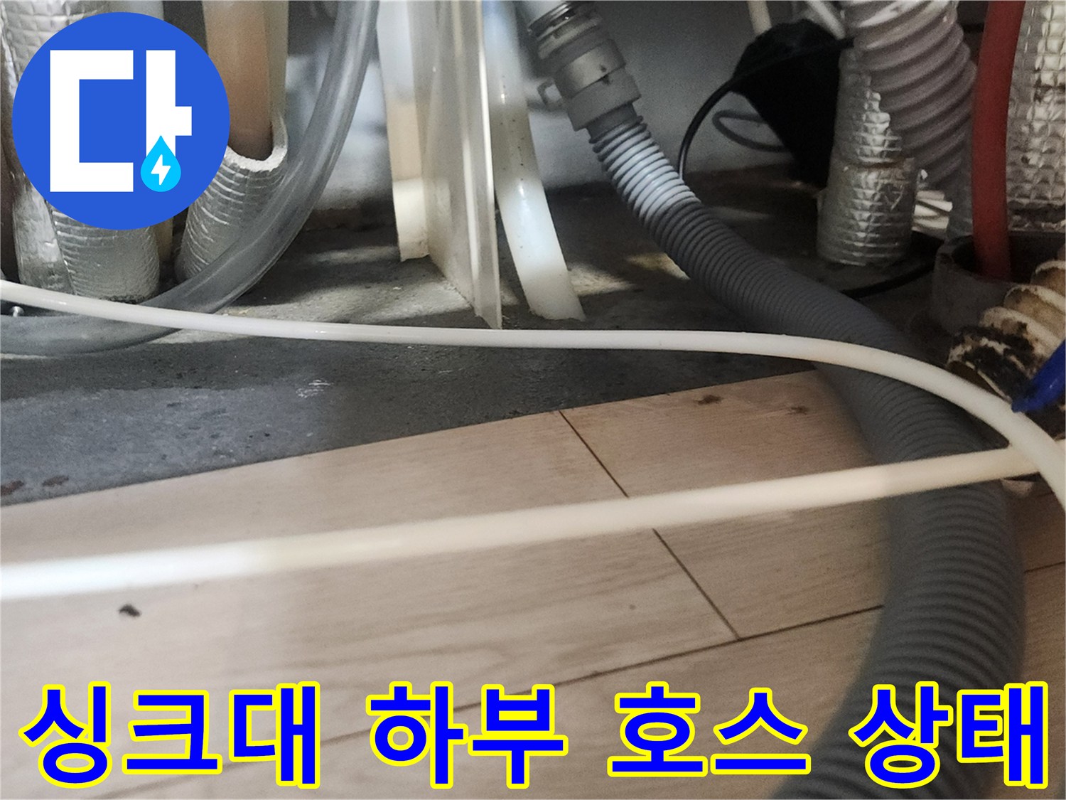 주방 싱크대 아래쪽의 복잡하게 얽힌 배수 호스들