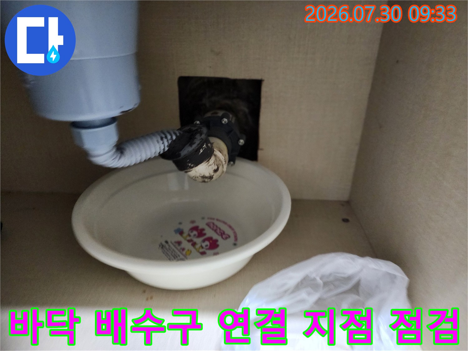 싱크대 아래 노출된 하수관과 호스 연결 구간을 정밀하게 촬영함