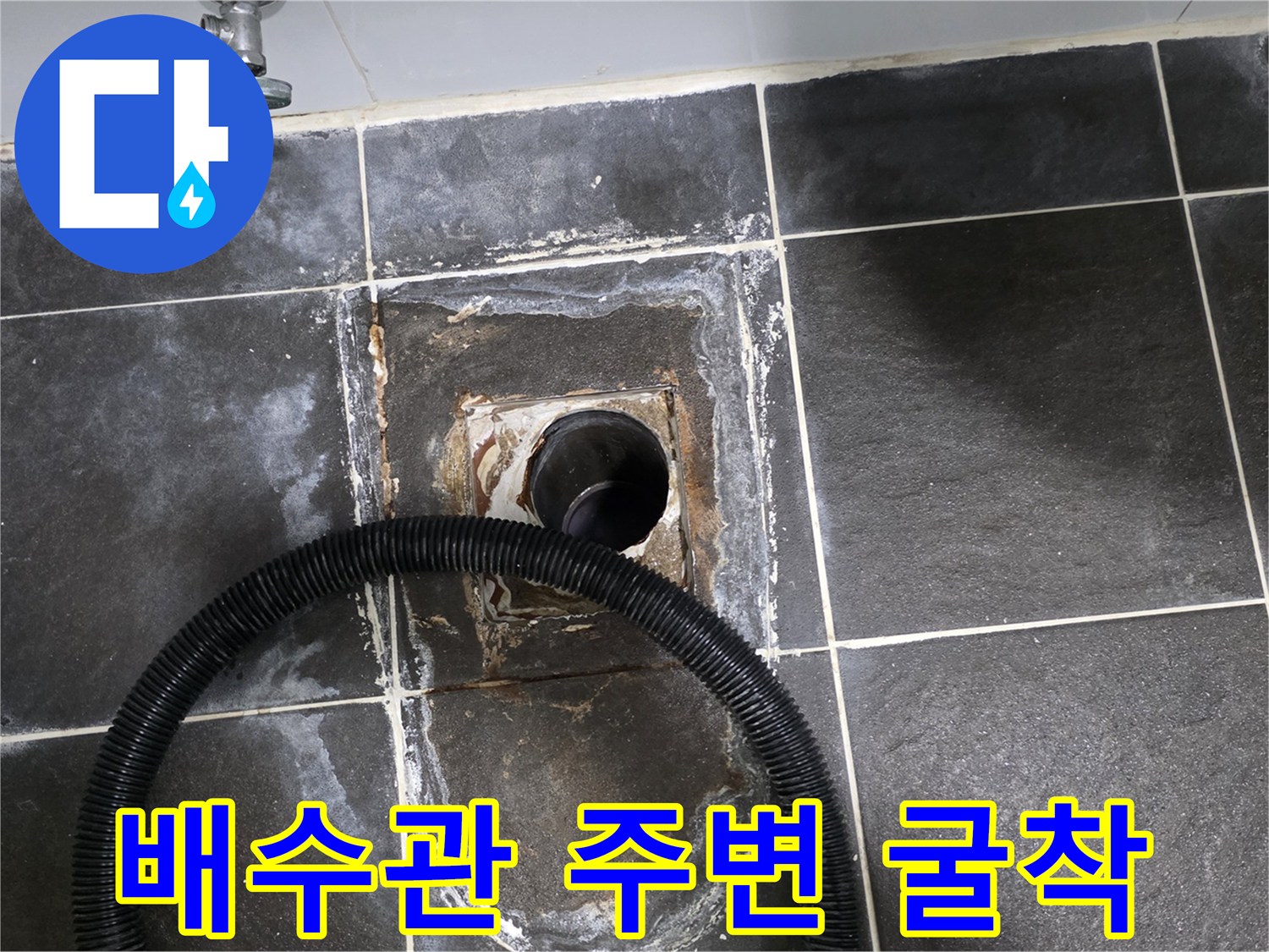 타일 아래 노출된 배수구 파이프와 주변 토사
