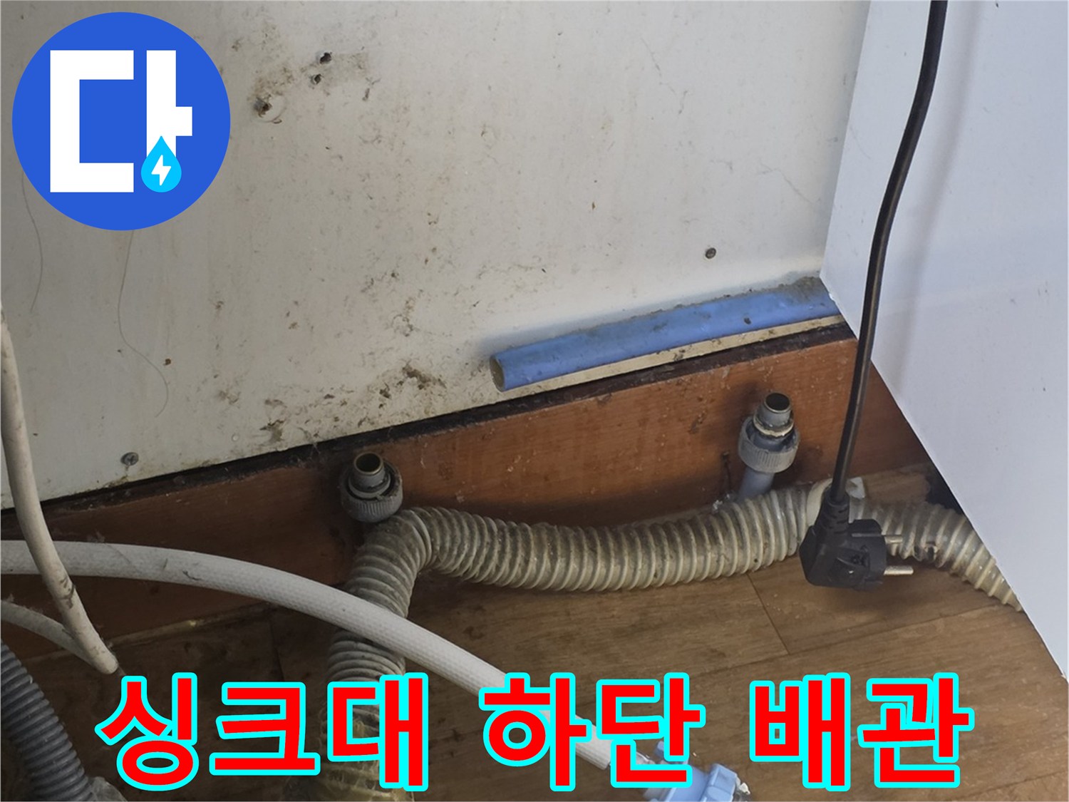 노후된 급수 호스와 연결 부속이 복잡하게 얽혀 있는 싱크대 내부 모습