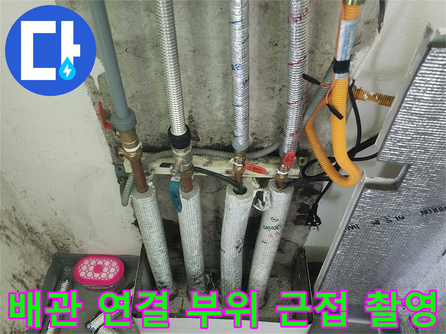 금속 보온재로 감싸진 다수의 배관과 노란색 호스 구조