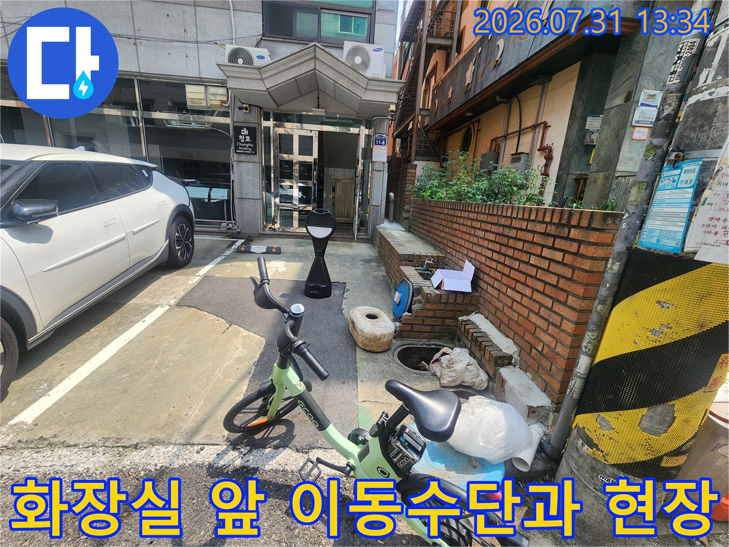 화장실 입구 앞에 주차된 전기 자전거와 건물 외벽