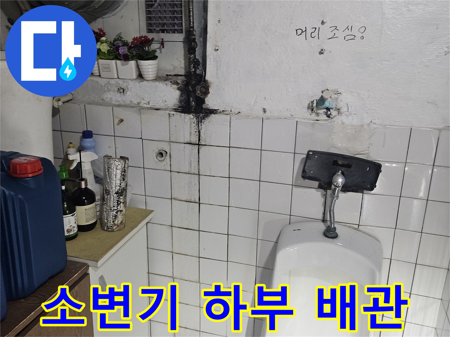 화장실 소변기 아래쪽의 부식된 금속 연결 배관 모습