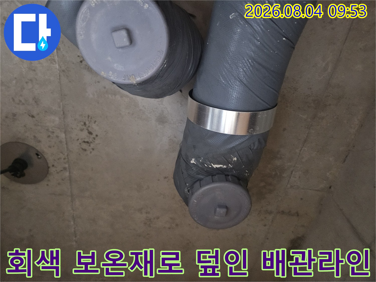 회색 재질의 보호층과 금속 지지대가 있는 배관 연결 구조