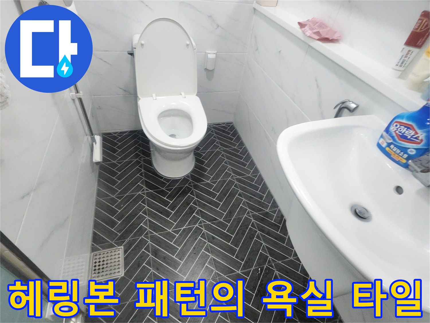 어두운 색상의 헤링본 타일과 흰색 변기 설치 모습